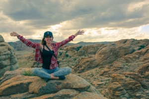Travel Mongolia a woman sitting on a rocky mountain with her arms wide open