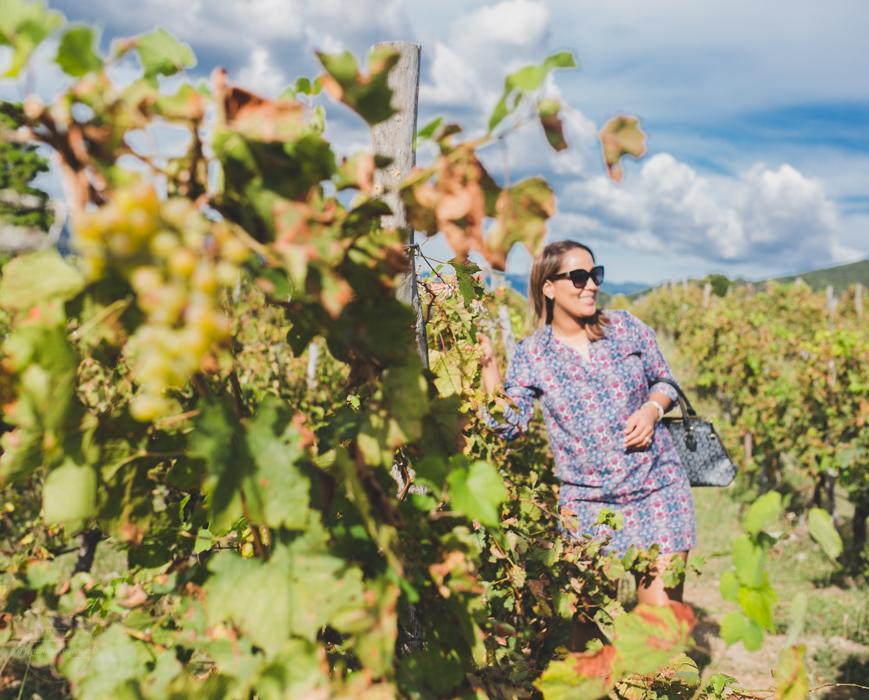 A woman beside one of the amazing vines filled with grapes that you'll find at the Ocoa Bay Vineyard.