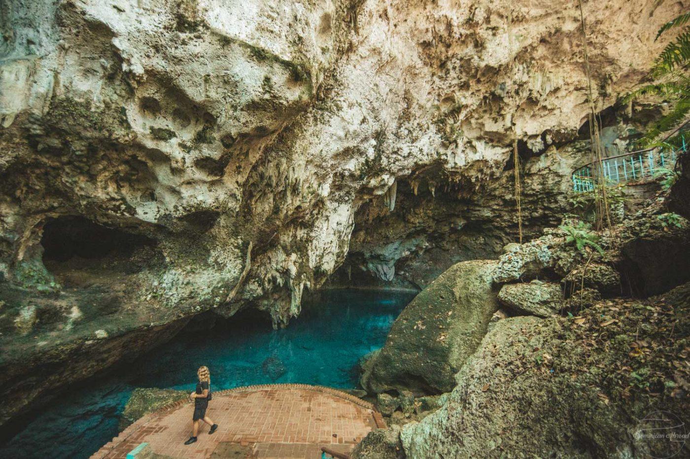 A person admiring the waters and cave of Los Tres Ojos.