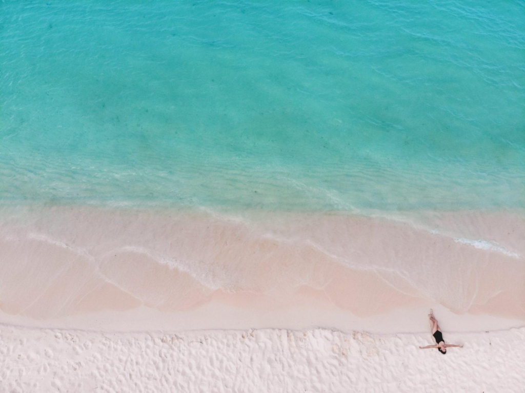 A person walking along the pristine sand and turquoise blue water of bahia de las aguilas, one of the best places to visit in the Dominican Republic.