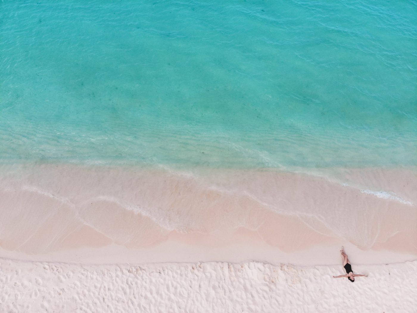 A person lying down on the pristine sand by the turquoise blue water of Bahia de las Aguilas, one of the best places to visit in the Dominican Republic.