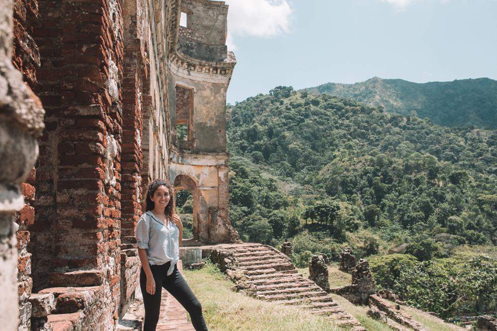 A woman at Sans Souci Palace in Haiti with mountains in the background