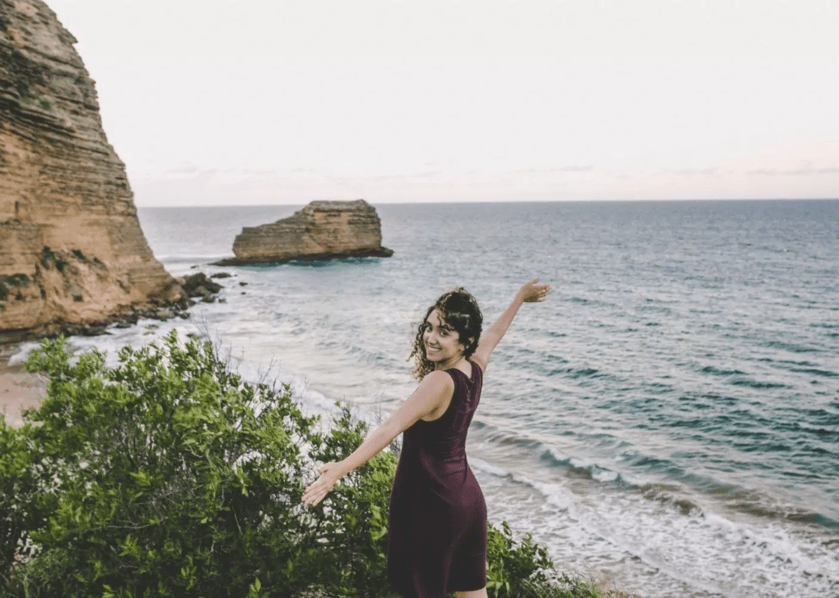 A woman spreading her arms open with the view of the sea in the background in Monte Cristi.