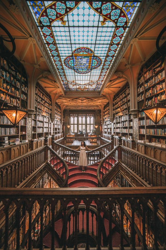 A woman standing on a staircase in Livraria Lello in Porto