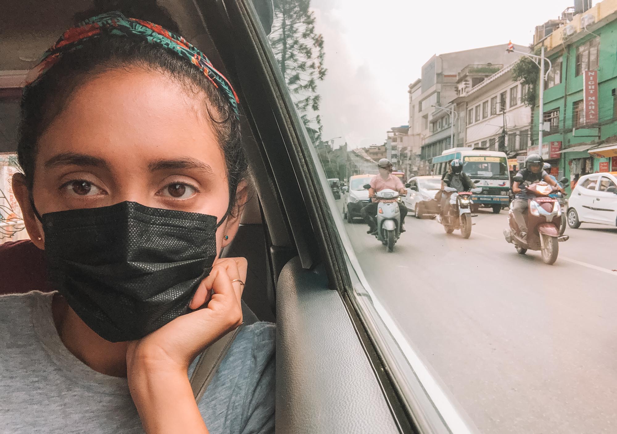 A woman wearing a black face mask inside a car on a street in Kathmandu pollution.