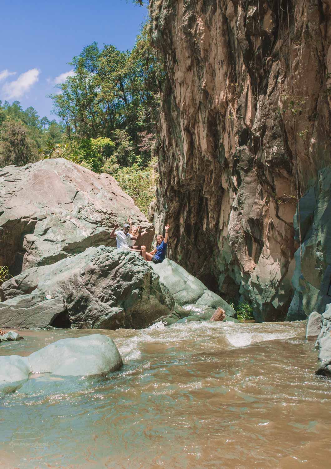 People sitting on a rock near Jimenoa I Waterfall.