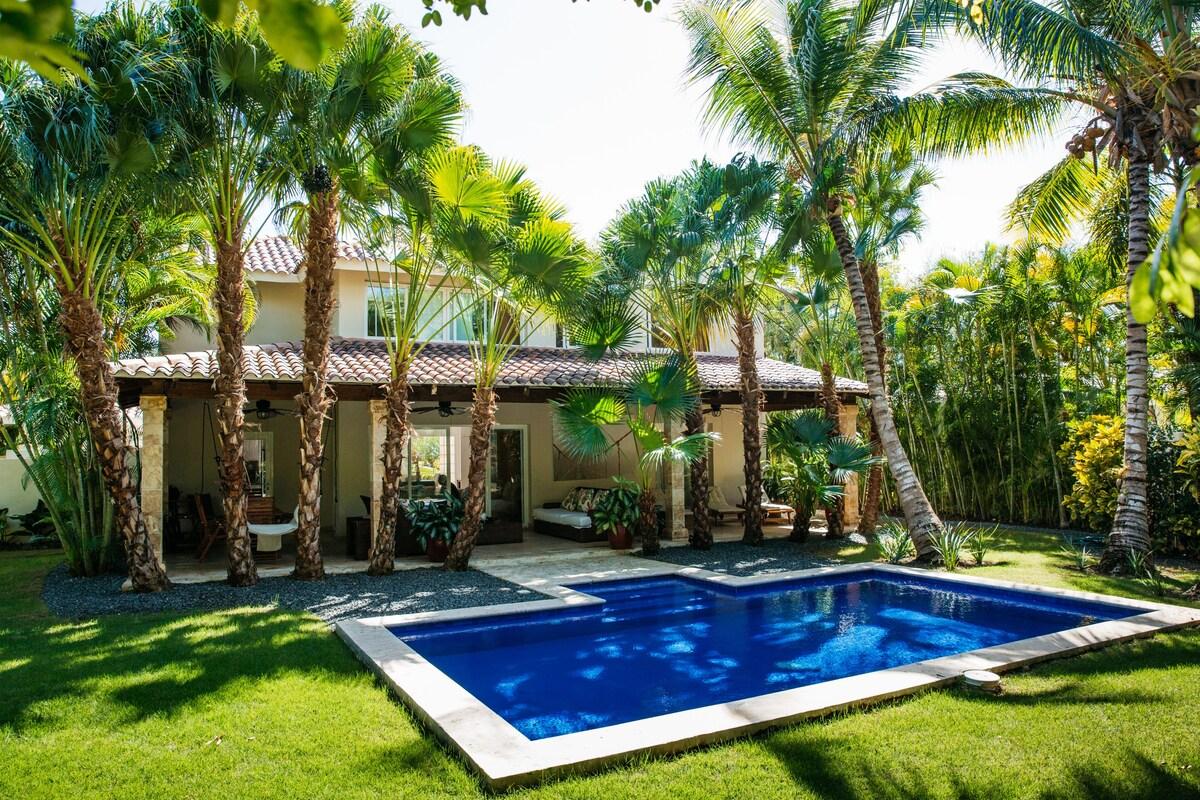 A villa with swimming pool surrounded by palm trees.