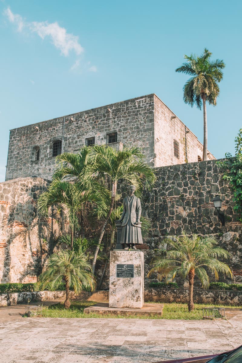 A statue with building and trees in the background in La Zona Colonial.