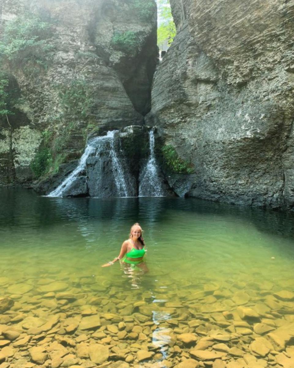 A woman standing in the natural pool in front of Mine Kill Falls, one of the waterfalls in New York State.