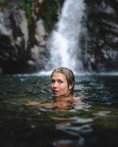 woman swimming in bish bash waterfalls looking back