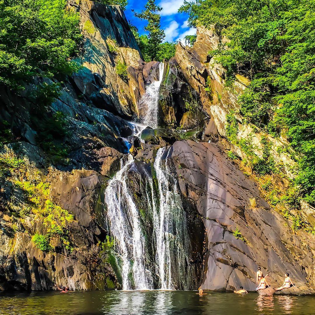 Waterfalls on high rocks surrounded by trees.