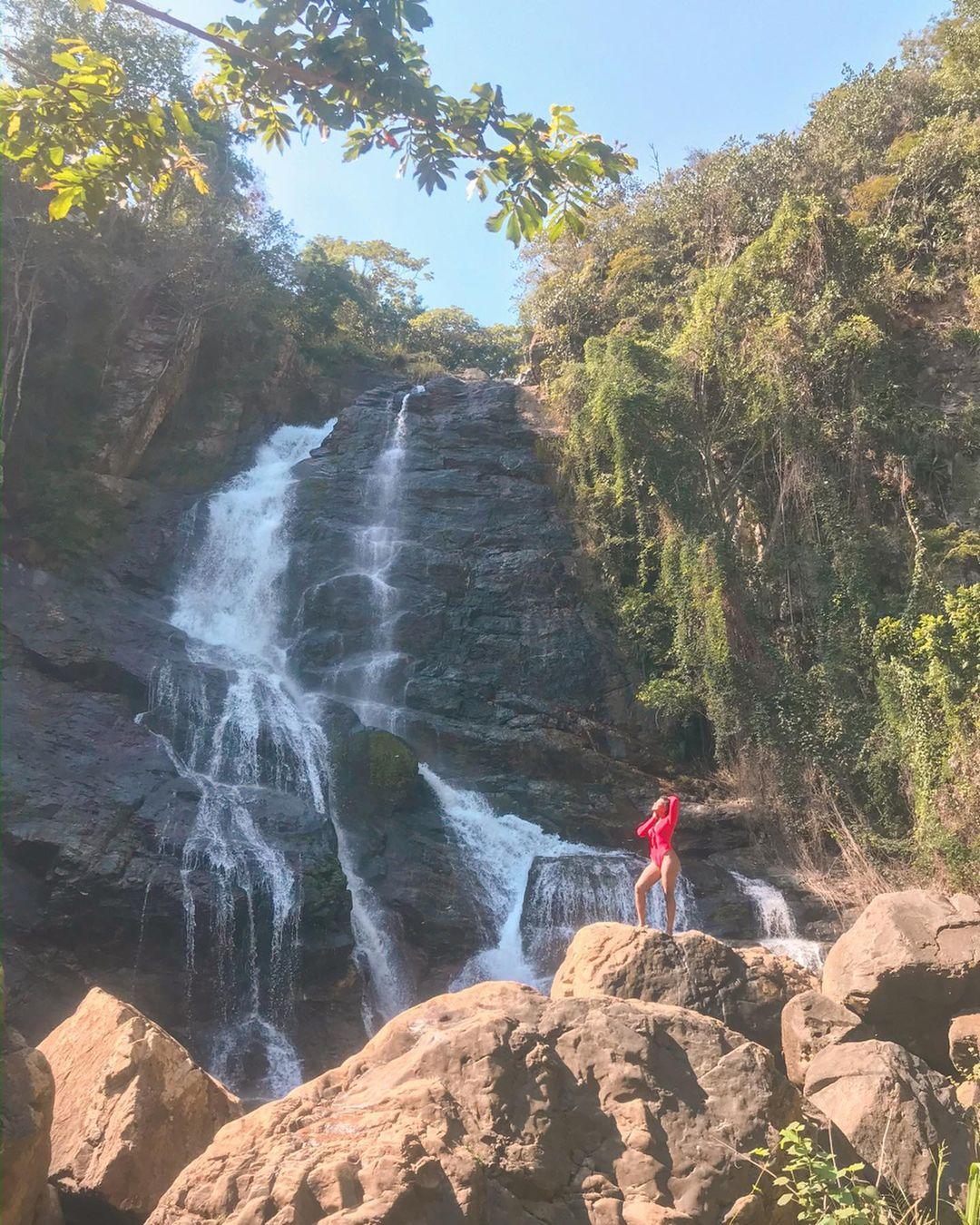 A woman standing on a giant rock near a waterfall at San Jose de las Matas.