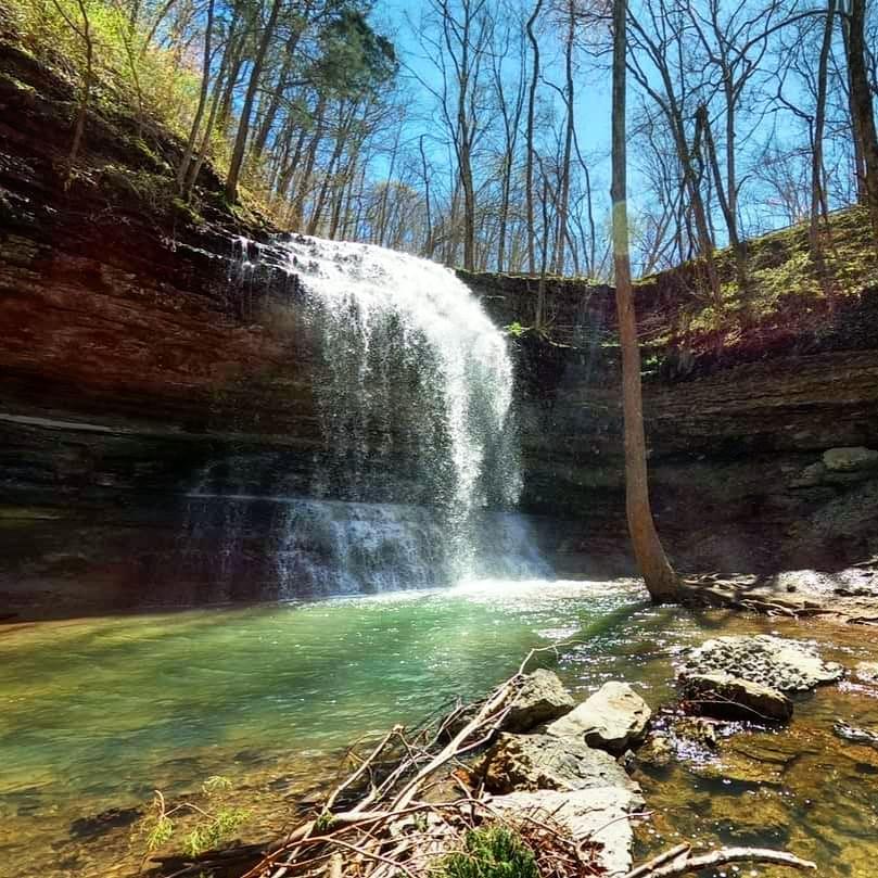 a waterfall with a green pool