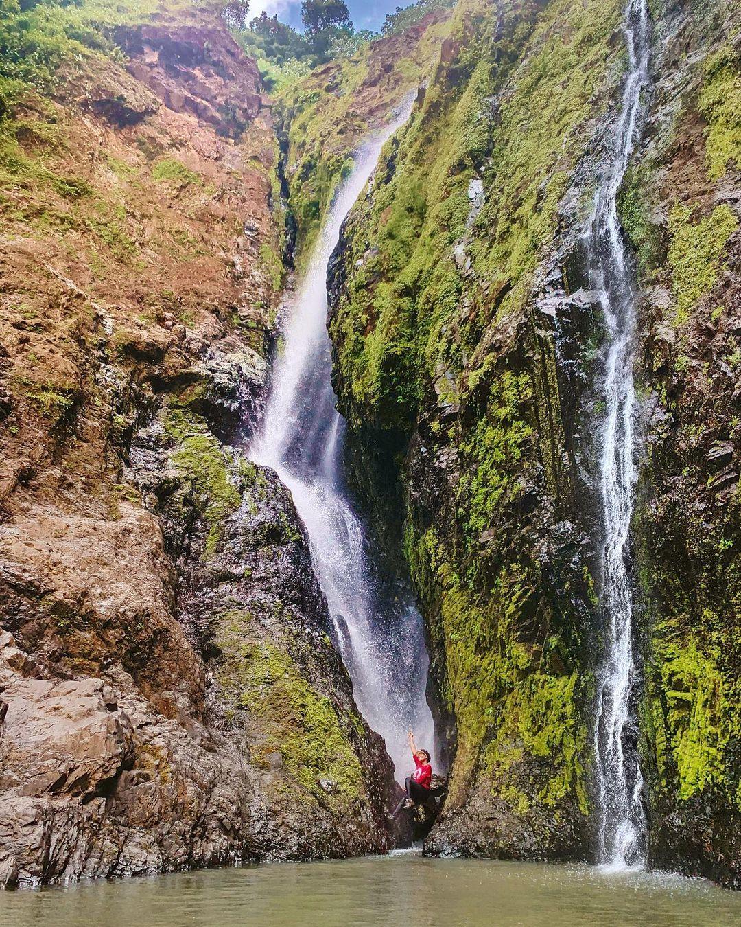 A woman sitting underneath a waterfall in Punta Cana, Dominican Republic.
