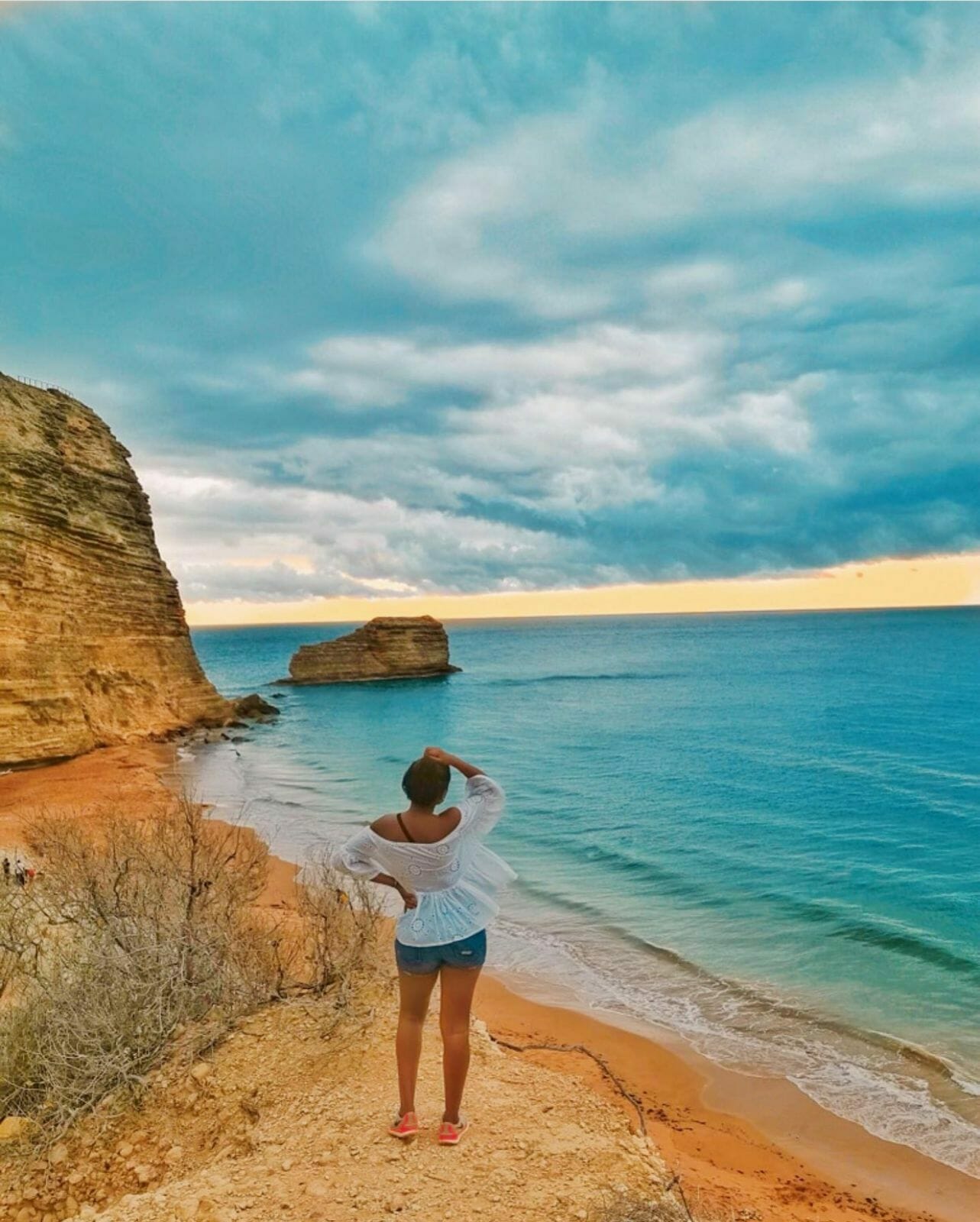 A woman standing on a rock looking at the sea at Playa El Morro.