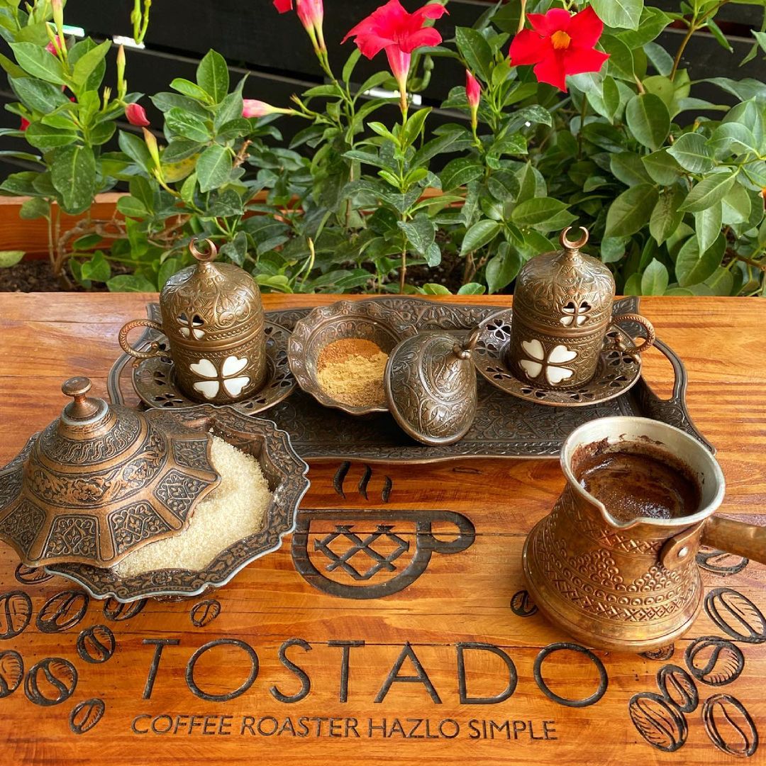 Drink and condiments in metal containers on a wooden table at a restaurant in Jarabacoa.