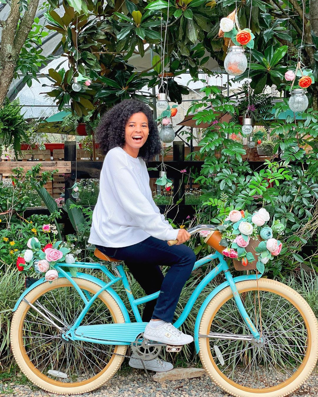 A woman sitting on a bicycle at a garden in Jarabacoa.