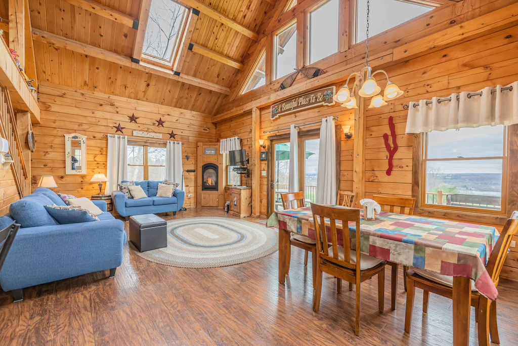 The inside of a log cabin with furniture and high roof.