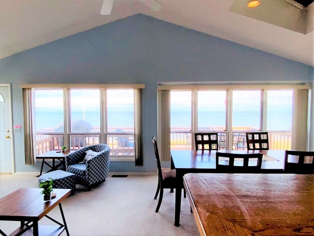The inside of a house with a view of a lake outside through windows.