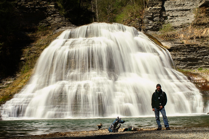 A guy standing by a waterfall in the Finger Lakes.