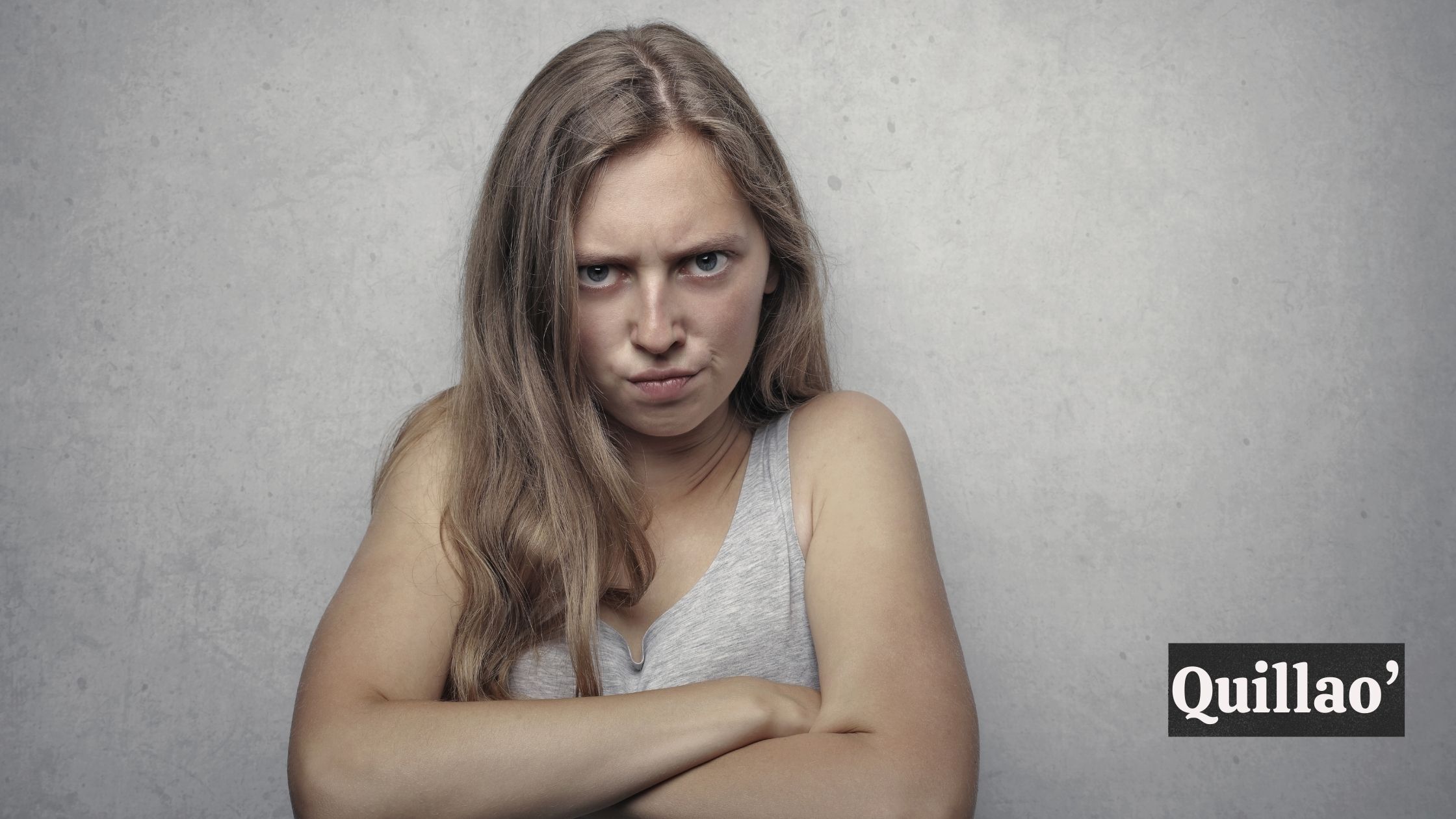 A woman with an angry expression folding her arms together; "Quillao'" tetx in image.