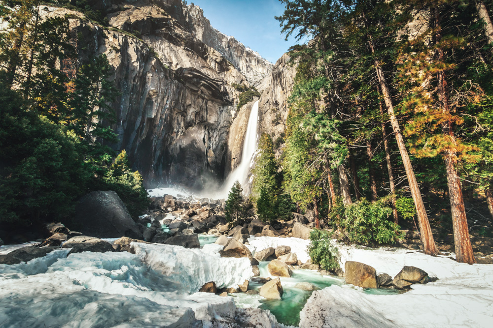 Waterfalls flowing through a rocky river surrounded by trees.