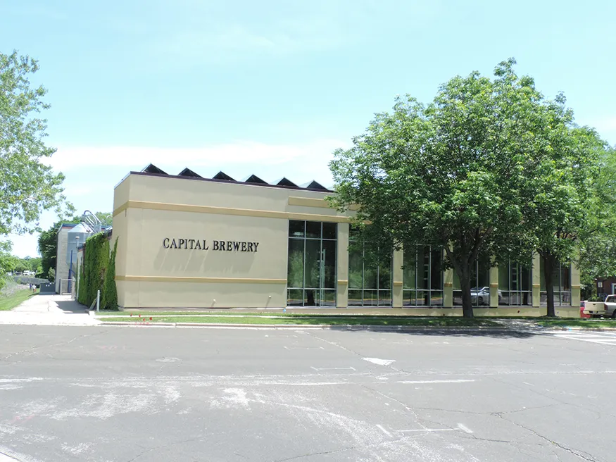 Building of the Capital Brewery from the outside. Yellow short building with lot of windows.