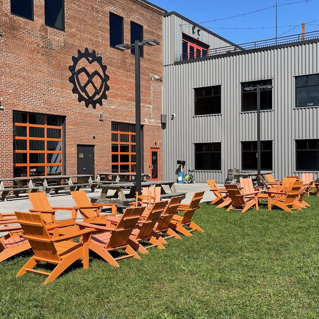 Exterior part of the brewery including garden with big chairs and facade.