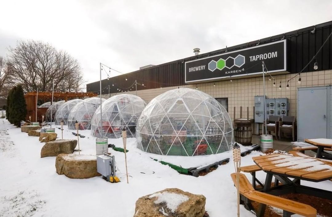 Front yard of the brewery during winter covered with snow and transparent cupolas where you can sit inside and enjoy drinking beers.