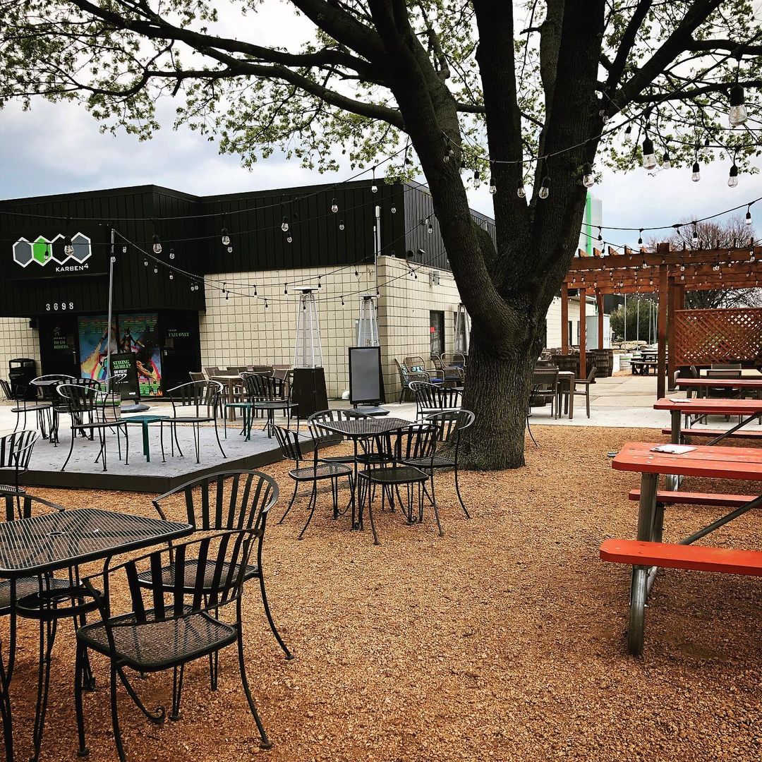 Front yard of the brewery with beautiful big tree and tables and chairs all around.