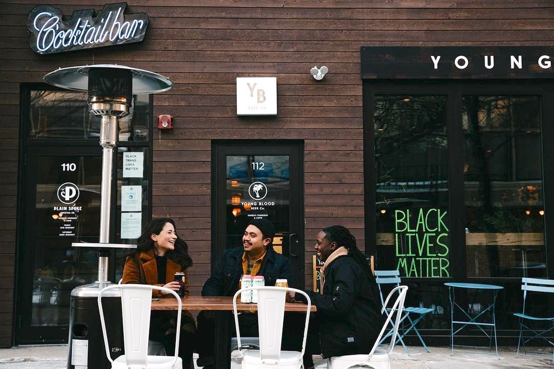 Three friends sitting in front of the brewery and drinking beers.