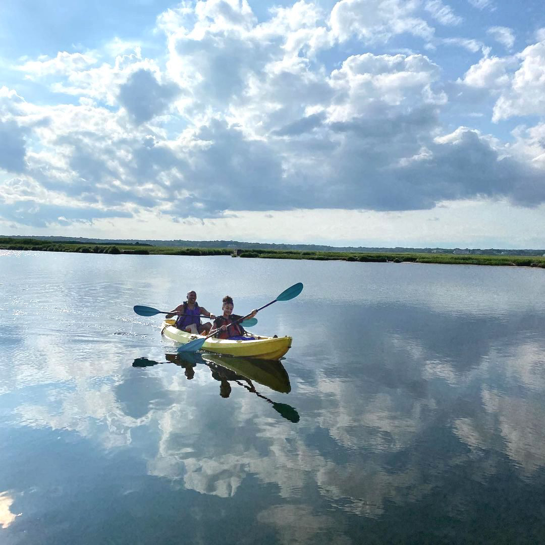 GIrl and a boy kayaking in the middle of the lake.
