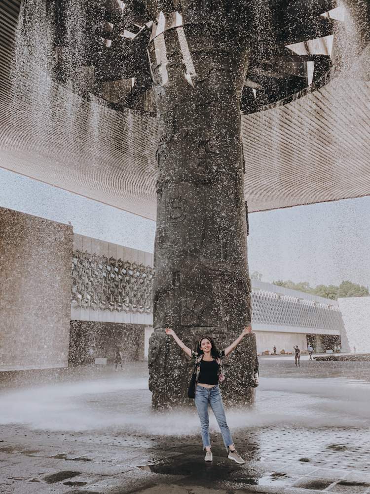 Woman under a man-made waterfall at National Anthropology Museum in Mexico City.