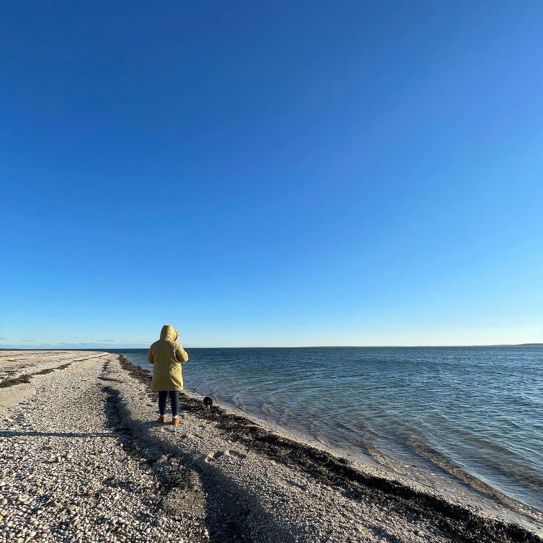 Undefiend person wearing huge jacket walking at the shore.