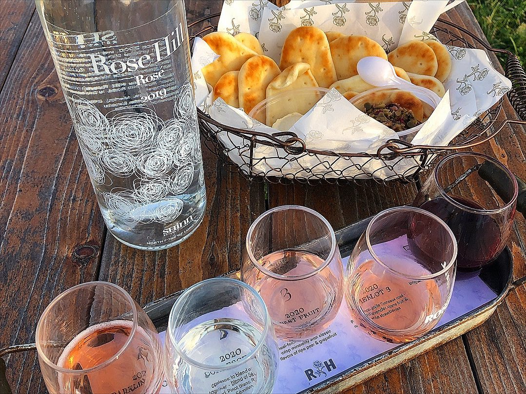 Table with glasses for casting wine and some bread to eat. Beautiful bottle of the water with winery's label.