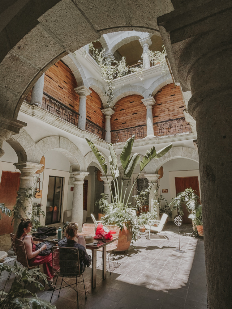 People sitting at a table chatting at a courtyard of a cafe in Oaxaca, Mexico.