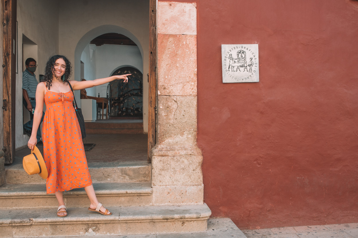 A woman in orange dress outside the The Instituto de Artes Gráficas building in Oaxaca, Mexico.