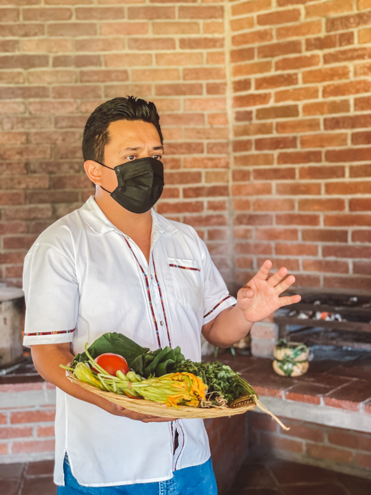 A man holding vegetables on a Oaxacan cooking class.
