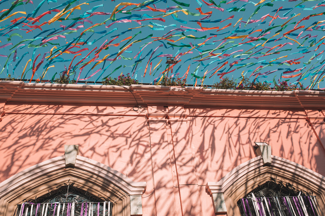 A pink building in Oaxaca decorated with colorful ribbons.