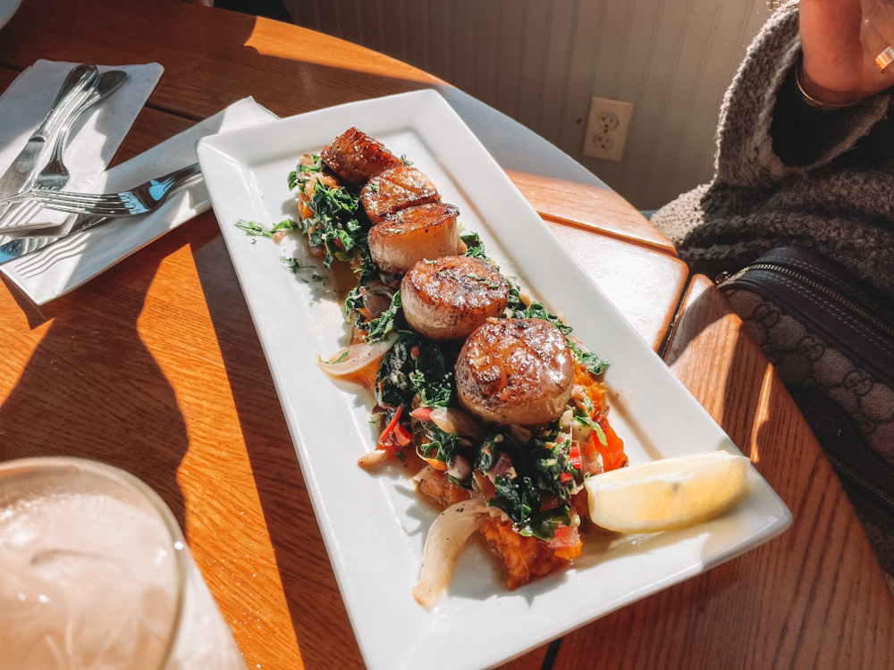 Scallops over sweet potatoes on a rectangular plate.
