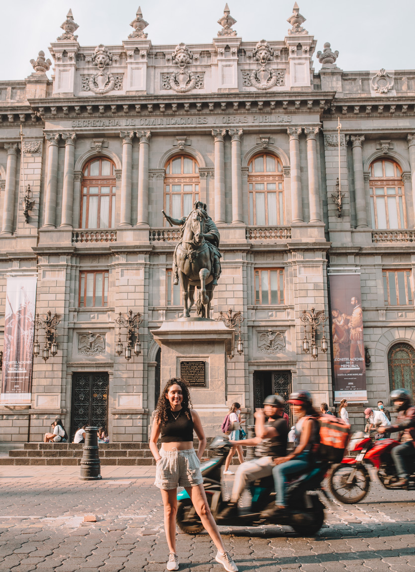 People standing, sitting, and riding motorcycles outside the National Art Museum in Mexico City.
