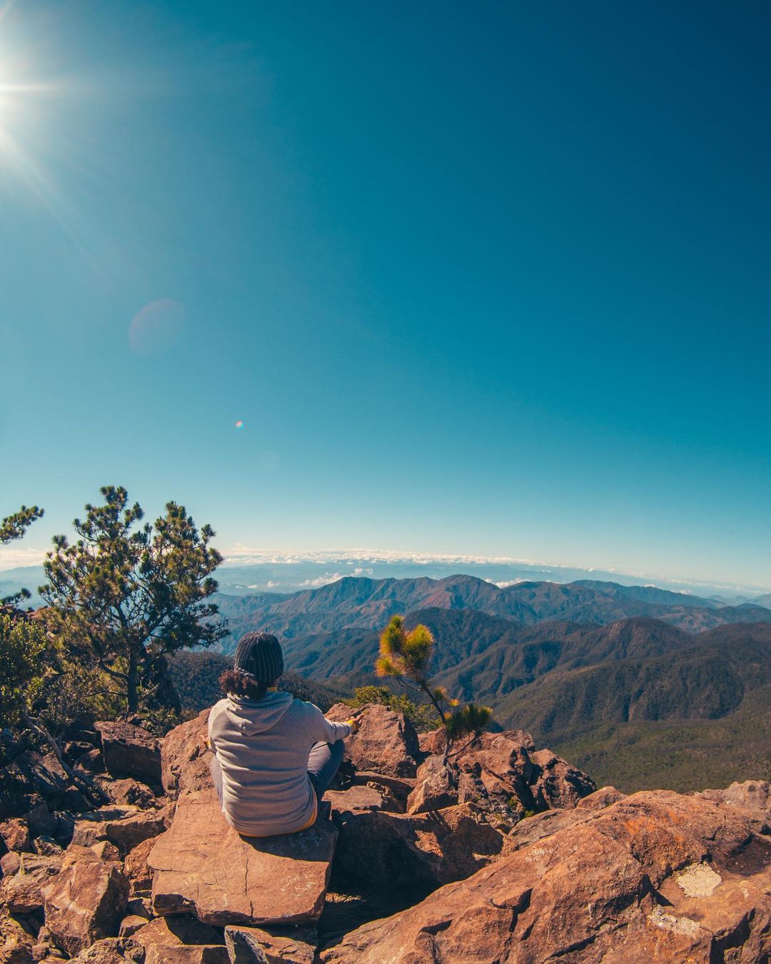 A person sitting on the rocks at Pico Duarte looking at a view.