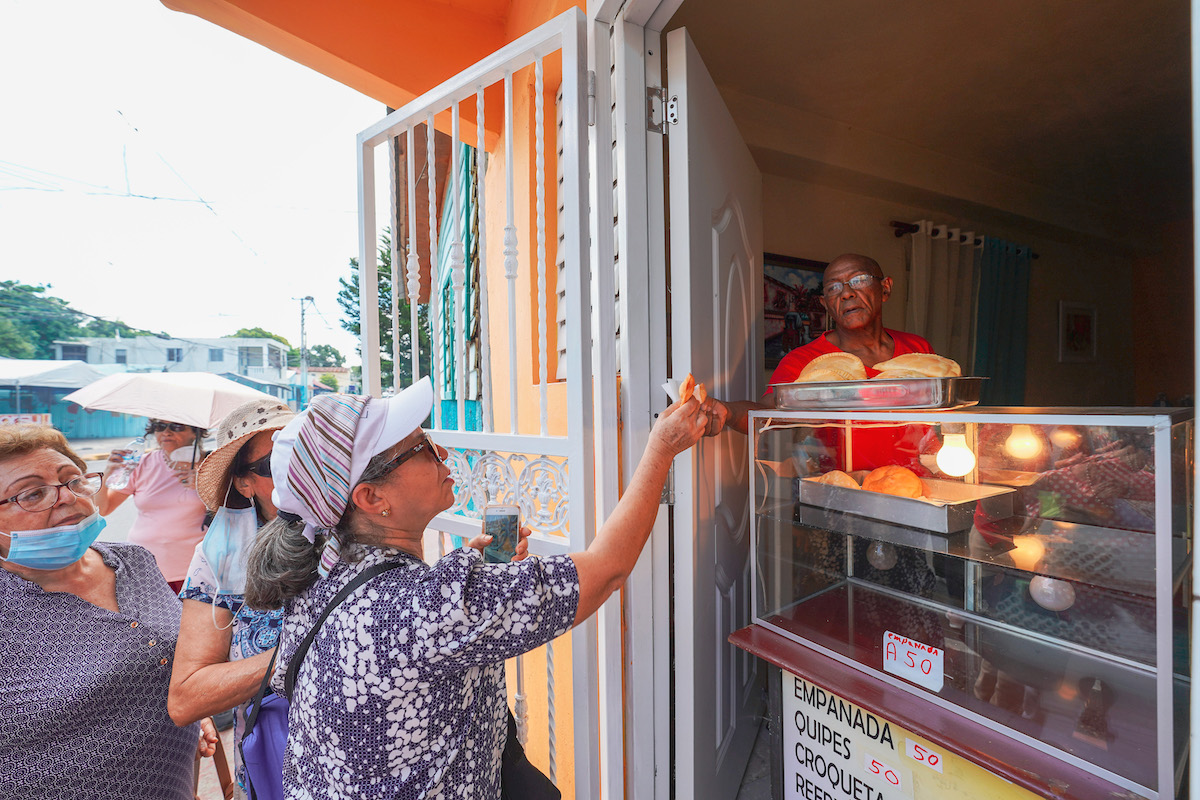 Women buying empanadas at a shop manned by an old man.