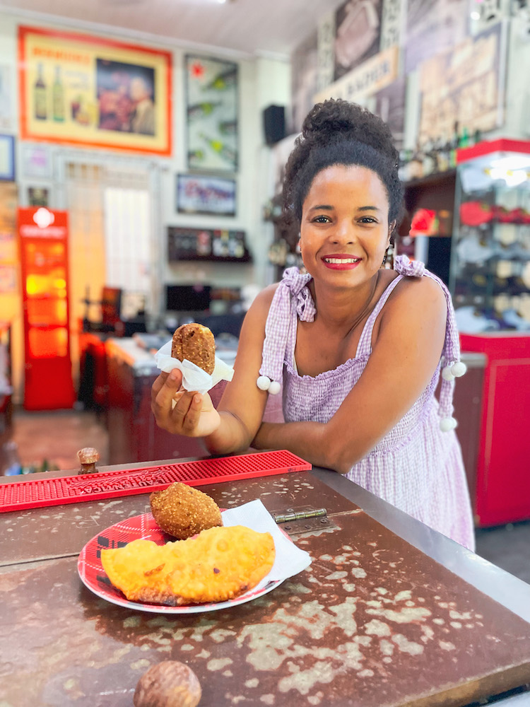A woman holding a piece of a quipes at bar in Santiago, Dominican Republic.