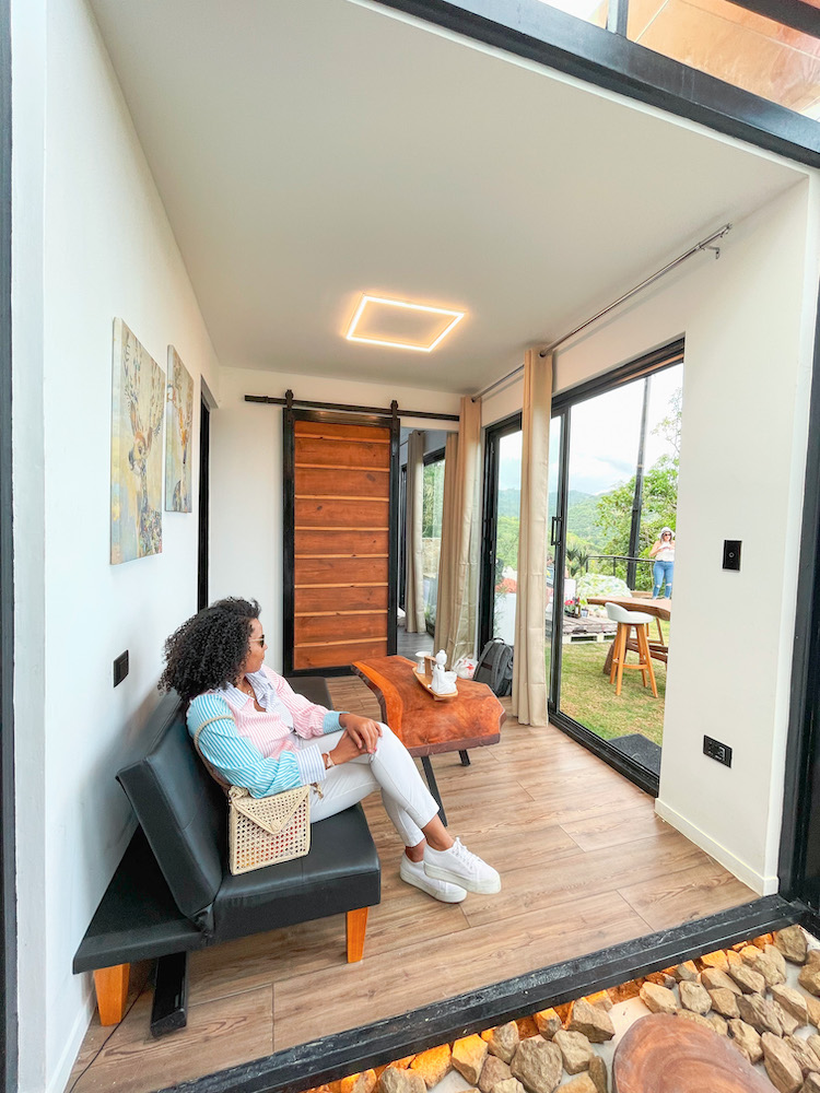 A woman sitting at a seating area of a shipping container accommodation.