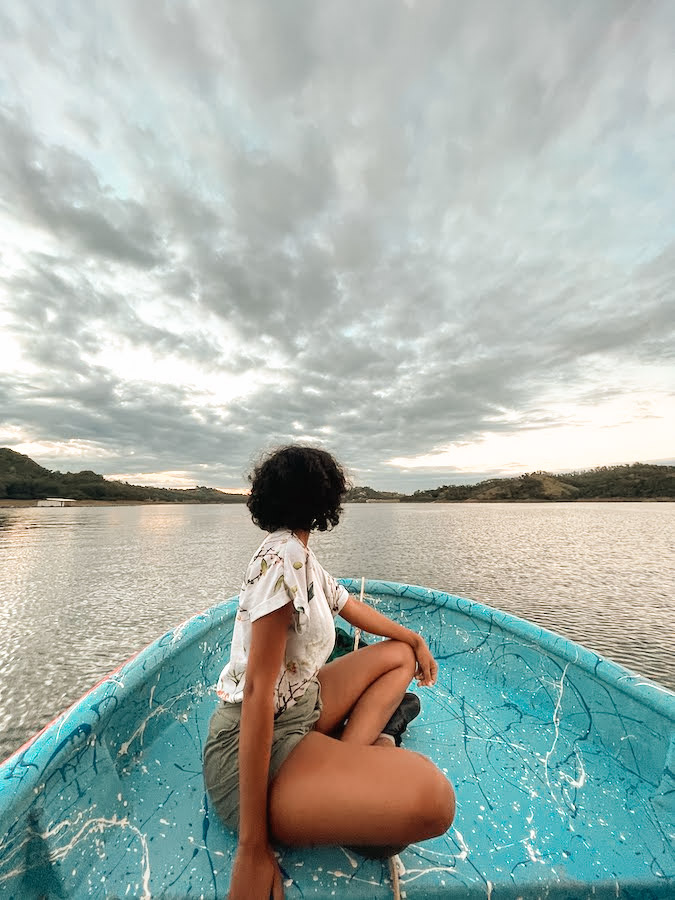 A woman sitting on a blue boat at Presa de Tavera dam.