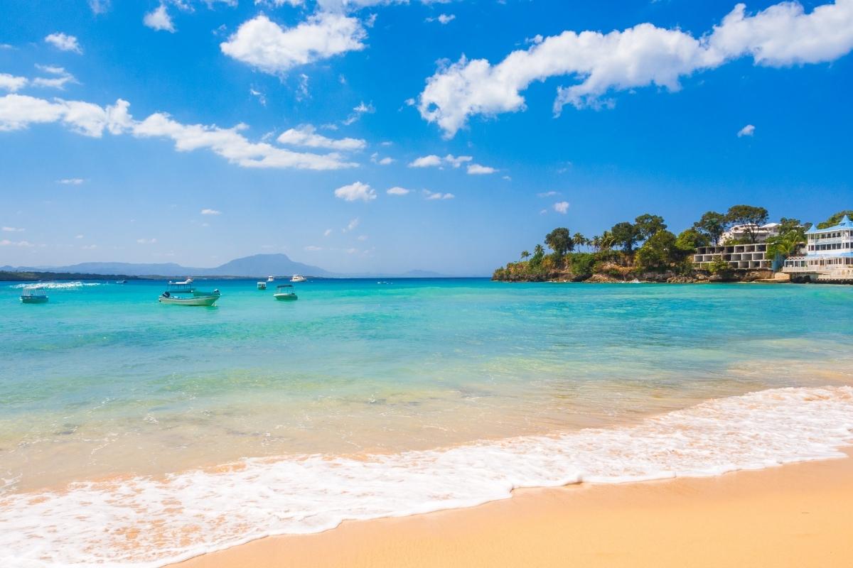 Sosua Beach with clean sand, blue waters, and boats.