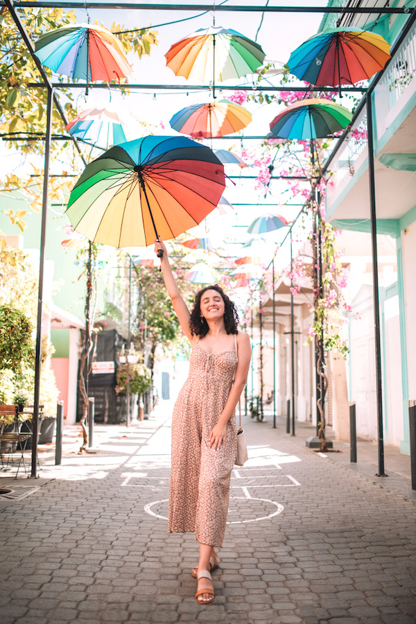 A woman holding a rainbow-color umbrella on a street in Puerto Plata, Dominican Republic.