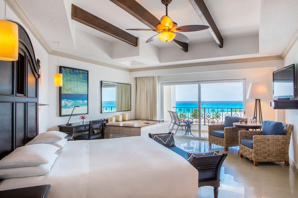 A bedroom with furniture and bathtub and a view of the sea from the window.