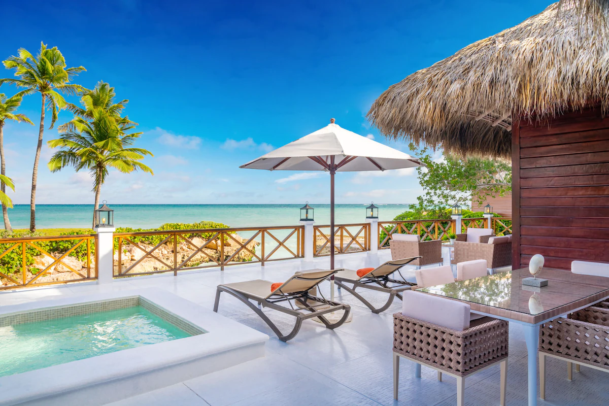 A small outdoor pool area with chairs and view of the beach at a resort in the Dominican Republic.